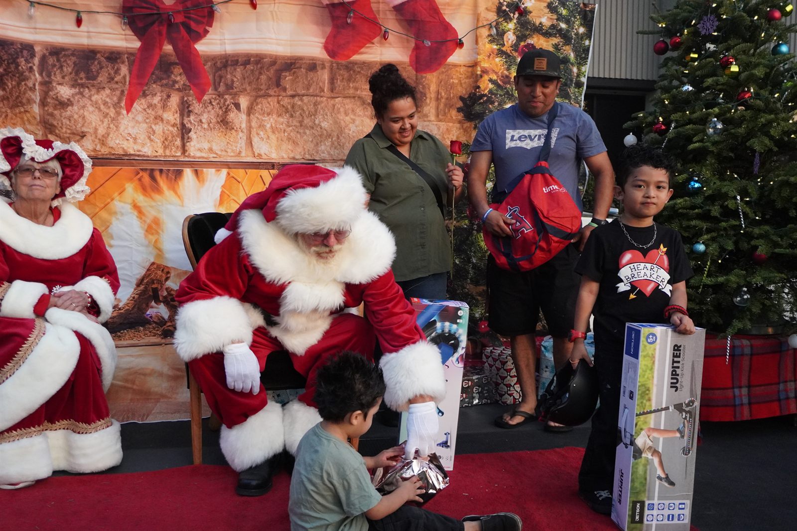 Santa handing a wrapped gift to a child at the Christmas Family Drive